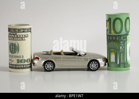 Un modello di auto tra i rotoli del dollaro e le banconote in euro Foto Stock