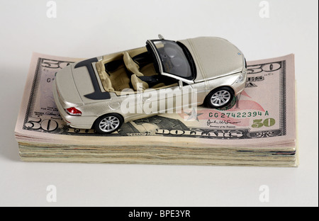 Un modello di auto su una pila di 50-dollaro banconote Foto Stock