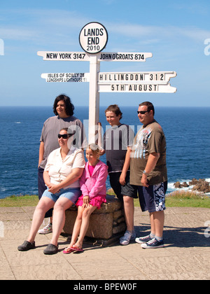 Famiglia avente le foto scattate nella parte anteriore del segno posto al Land's End, Cornwall, Regno Unito Foto Stock