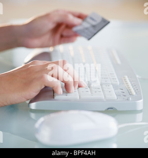 Mani carta di credito durante la digitazione sulla tastiera del computer Foto Stock