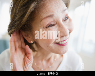 Donna Giapponese l ascolto con la mano vicino a orecchio Foto Stock