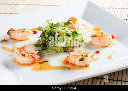 Sauté di gamberi con chill, zenzero e coriandolo con un nido di baby insalata in foglie Foto Stock