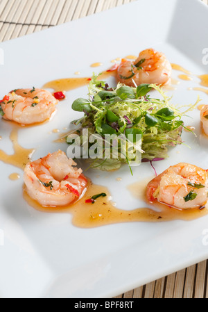 Sauté di gamberi con chill, zenzero e coriandolo con un nido di baby insalata in foglie Foto Stock