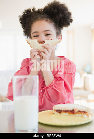 Razza mista ragazza sandwich di contenimento nella parte anteriore del viso Foto Stock