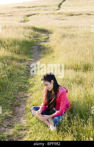 Ispanico ragazza seduta nel campo Foto Stock