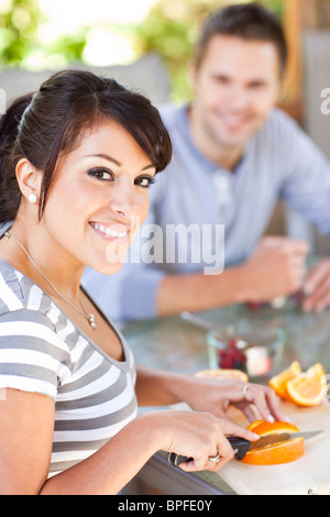 Donna ispanica per affettare le arance sul patio Foto Stock