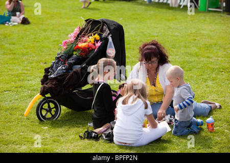 Regno Unito, Inghilterra, Merseyside Southport Flower Show, giovane famiglia godendo picnic su erba in sole avendo comprato i fiori Foto Stock