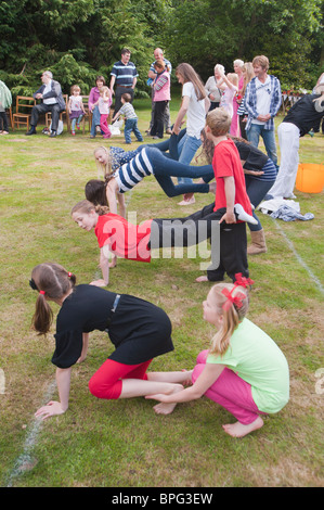 I bambini di competere in carriola gara in un villaggio di fete in Weston , Suffolk , Inghilterra , Gran Bretagna , Regno Unito Foto Stock