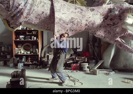 Uomo che porta enorme braccio essendo realizzata in cartapesta in preparazione per il carnevale di Viareggio Foto Stock