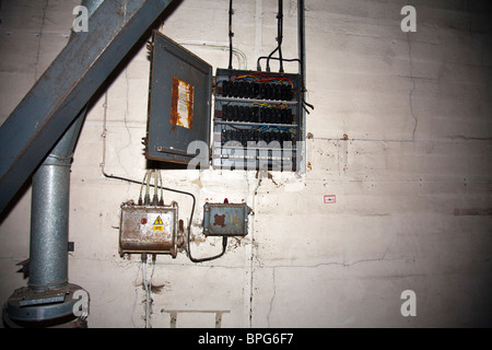 Pannello di controllo elettrico in una fabbrica abbandonata, fili e interruttori ovunque Foto Stock