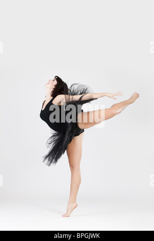 Bellissima ballerina femmina facendo split contro uno sfondo bianco Foto Stock