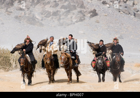 Il kazako eagle cacciatori con aquile reali sul modo per i cacciatori di Eagle Festival in Bayan-Ulgii nelle montagne di Altai Mongolia occidentale Foto Stock