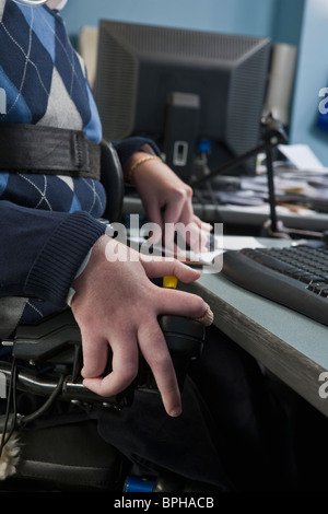 Imprenditore con distrofia muscolare di Duchenne in una sedia a rotelle motorizzata lavora in un ufficio Foto Stock