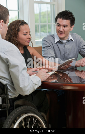 Non vedenti imprenditrice ispanica discutendo con due imprenditori in un ufficio Foto Stock