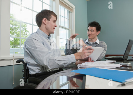 Imprenditore con lesioni del midollo spinale a discutere con il suo collega in un ufficio Foto Stock