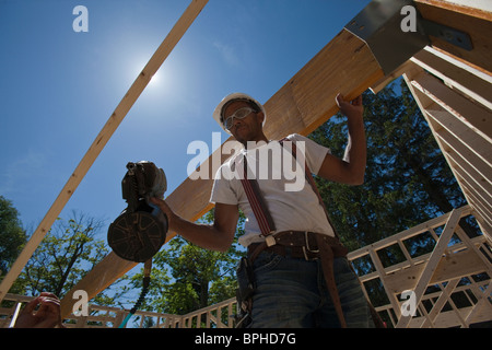 Carpenter utilizzando una pistola sparachiodi in corrispondenza di un sito in costruzione Foto Stock