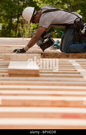 Carpenter utilizzando una pistola sparachiodi in corrispondenza di un sito in costruzione Foto Stock