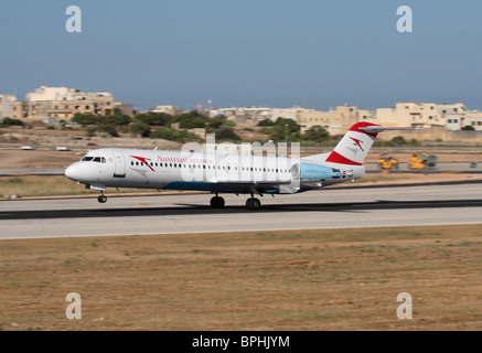 Frecce austriaco Fokker F100 jet del passeggero aereo sulla pista dell'Aeroporto Internazionale di Malta durante la fase di decollo Foto Stock