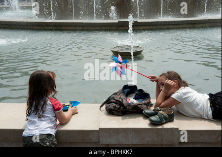 Due ragazze giocare su una fontana confine in una calda giornata estiva a Milano Italia Foto Stock