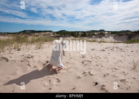 Una fotografa che scatta foto di paesaggi a Ludington Michigan, negli Stati Uniti, dal retro con fotocamera digitale ad alta risoluzione per adulti Foto Stock