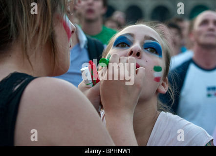 Appassionato di calcio dipingere i loro volti con bandiera italiana di colori mentre si guarda Italia 's gioco su grande schermo in Piazza Duomo Milano Italia Foto Stock