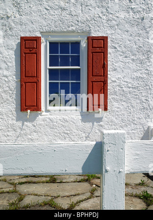 Vecchia finestra con persiane rosse e stucco bianco parete Foto Stock