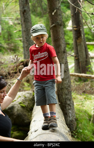 I bambini ad esplorare nella foresta - madre aiutare figlio oltre il torrente - parco nazionale Sumava Repubblica Ceca Foto Stock