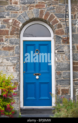 Dipinto di blu con pannelli porta anteriori con vetri ottone ritaglio respingente letterbox e manopola bianca della pietra casa costruita nel Regno Unito Foto Stock