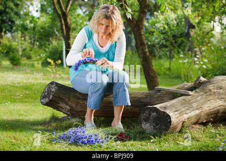 Donna che fa una ghirlanda di fiori blu Foto Stock