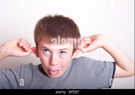 Un modello rilasciato una foto di un 10 anno vecchio ragazzo tirando una divertente faccia in studio Foto Stock