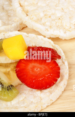 Torte di riso con frutta fresca a fette, su un sfondo di legno Foto Stock
