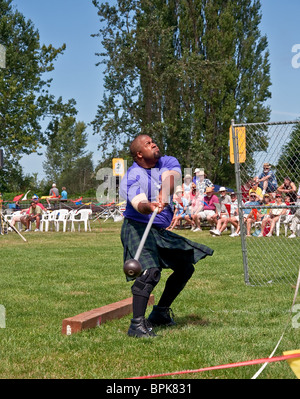 Questo americano africano l uomo partecipa al gioco scozzese conosciuta come martello toss indossando un kilt Scozzesi tradizionali Foto Stock