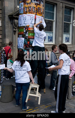 Persone mettere-up volantini promuovere una frangia in mostra il Festival di Edimburgo, Scozia. Foto Stock