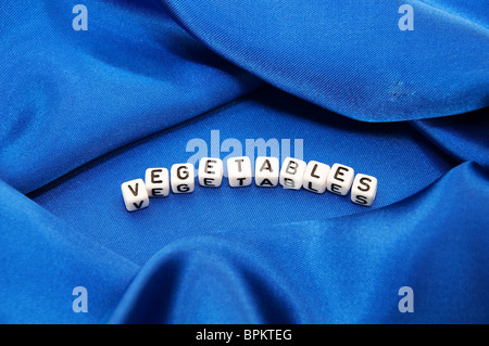 Royal Blue satinato con sfondo ricco di pieghe e grinze per tessitura è la parola verdura in cubo serie lettering Foto Stock