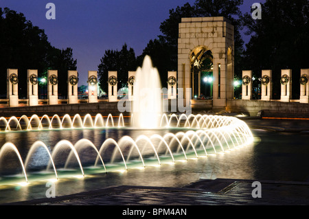 WASHINGTON DC, Stati Uniti: La fontana illuminata del National World War II Memorial sul National Mall di notte. La fontana, una caratteristica centrale del monumento, si riflette splendidamente sull'acqua calma, creando una serena e toccante scena notturna in onore di coloro che hanno prestato servizio nella seconda guerra mondiale Foto Stock