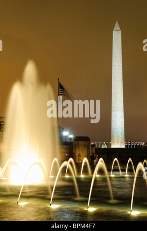 National World War II Memorial Fountain Washington DC // WASHINGTON DC - la fontana illuminata del National World War II Memorial si illumina sul National Mall di notte. Dedicato nel 2004, il memoriale onora i 16 milioni di americani che hanno prestato servizio nelle forze armate durante la seconda guerra mondiale e gli oltre 400.000 morti. La Rainbow Pool centrale con i suoi getti illuminati si trova tra i padiglioni Atlantico e Pacifico del monumento, che rappresentano i due teatri della guerra. I 56 pilastri di granito che circondano la piazza rappresentano gli stati e i territori degli Stati Uniti durante gli anni della guerra. Foto Stock
