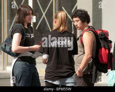 Una femmina di carità lavoratore smette di un uomo e di una donna in una strada di Glasgow al fine di iscriverlo a un addebito mensile donazione. Foto Stock