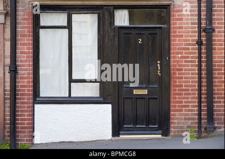 Victorian rivestite con pannelli di legno verniciato di colore nero in legno della porta anteriore e la finestra del mattone costruito casa a Llandrindod Wells Powys Mid Wales UK Foto Stock