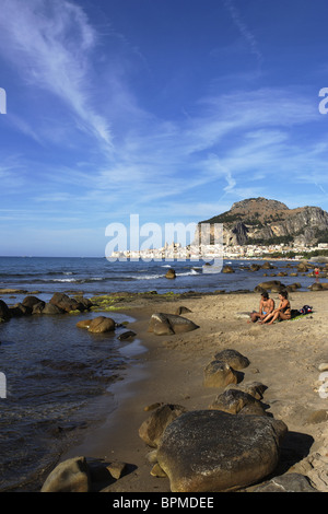 Coppia sulla spiaggia, vista a Cefalu con la Rocca di Cefalù, Cefaly, Sicilia, Italia Foto Stock