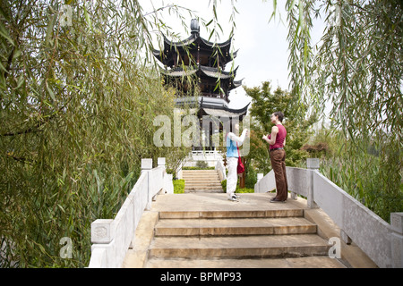 Giovane donna cinese e il turista tedesco a parlare su un ponte a Lianhuachi park, Kunming, Yunnan dalla Repubblica popolare di Cina e Asia Foto Stock