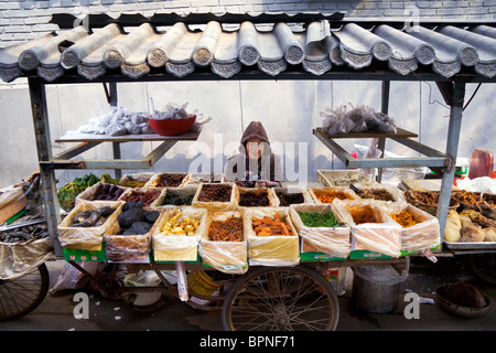 Una donna felice offerte il suo mercato alimentare in stallo i vecchi vicoli di Pechino. Foto Stock