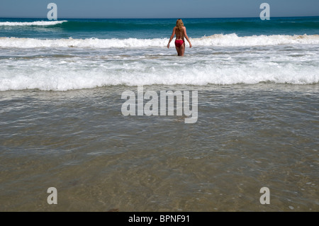 Vista posteriore di una donna che cammina fuori in mare Foto Stock