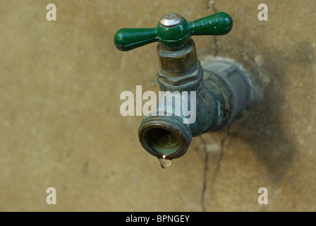 In vecchio stile rubinetto metallico con una goccia d'acqua. Foto Stock