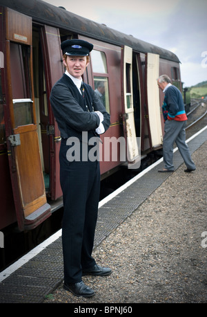 Porter in attesa accanto al treno sulla linea di papavero north norfolk Inghilterra Foto Stock