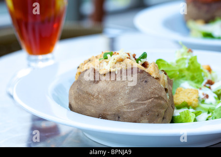 Patate al forno con pollo al curry e insalata caesar Foto Stock