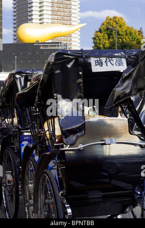 Giapponese carrelli di taxi di fronte al "fiamma" di Asahi Breweries, Sumida City, Tokyo, Giappone Foto Stock