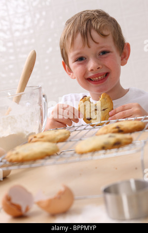 Giovane ragazzo in cucina mangiare cookie Foto Stock