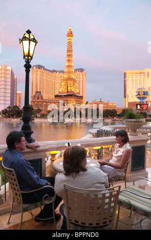 Gli ospiti dell'Hotel Bellagio in seduta la Fortuna bar guardando verso il Paris Hotel, la striscia di Las Vegas Nevada USA Foto Stock