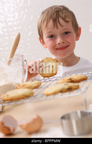 Giovane ragazzo in cucina mangiare cookie Foto Stock