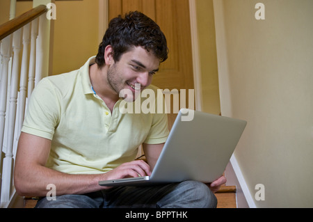 Giovane uomo Appartamento affitto casa condividi università degli studi universitari 19-21 anni ragazzo WiFi su scale di lavoro App Skype Facebook etc sul suo computer portatile Foto Stock